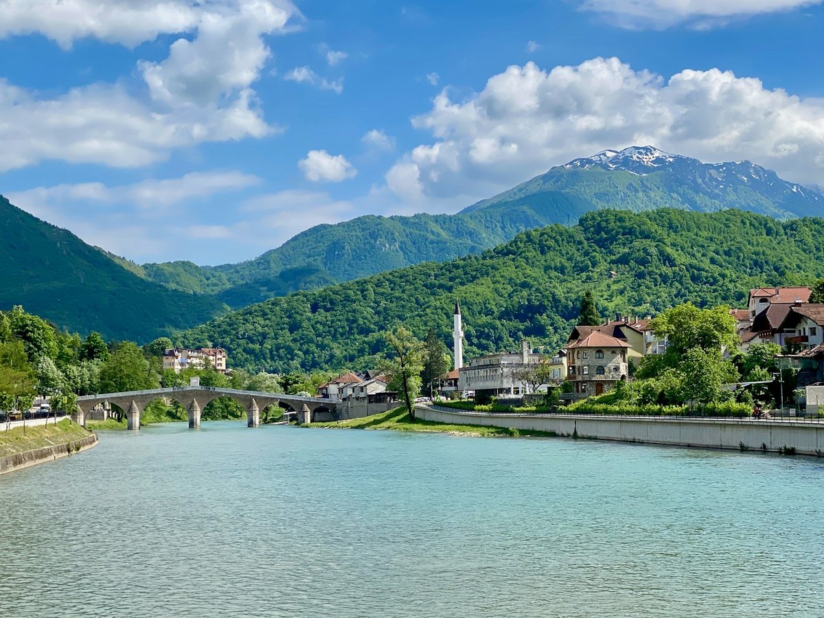 A boat on the Neretva River near Konjic, with green mountains rising under a blue sky