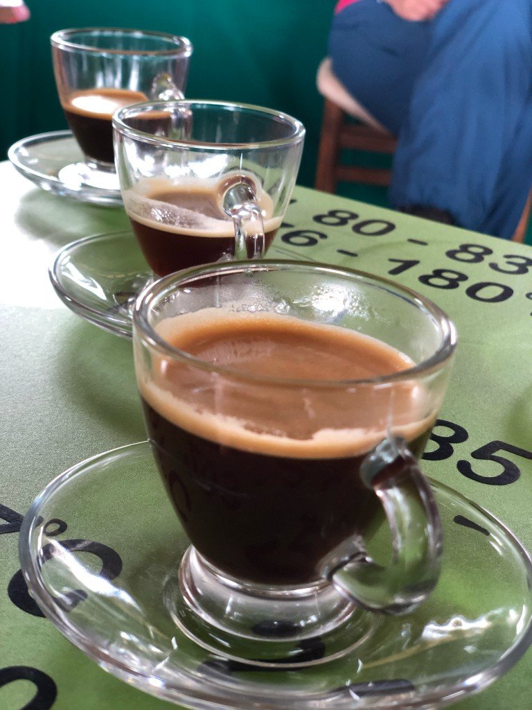 Three glasses of espresso lined up on a tasting table at Hacienda Guayabal in Colombia's coffee region