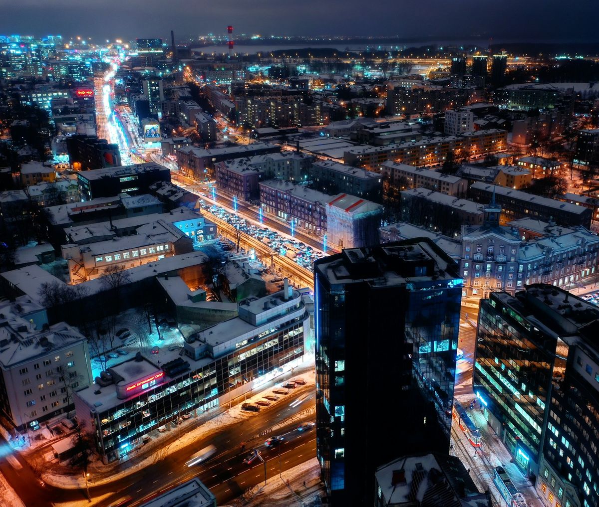 Aerial night view of snow-covered Tallinn streets, traffic lights and modern buildings