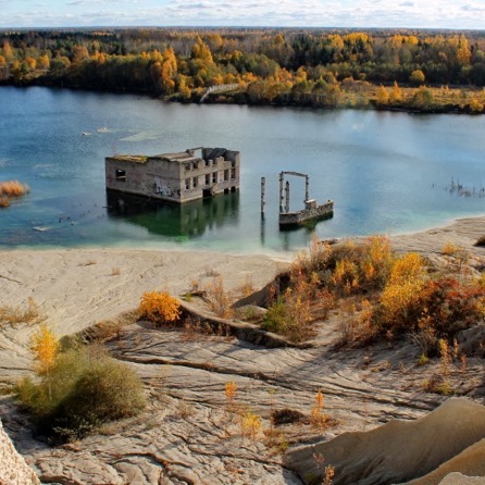 Turquoise flooded Rummu quarry and pale spoil hill outside Tallinn