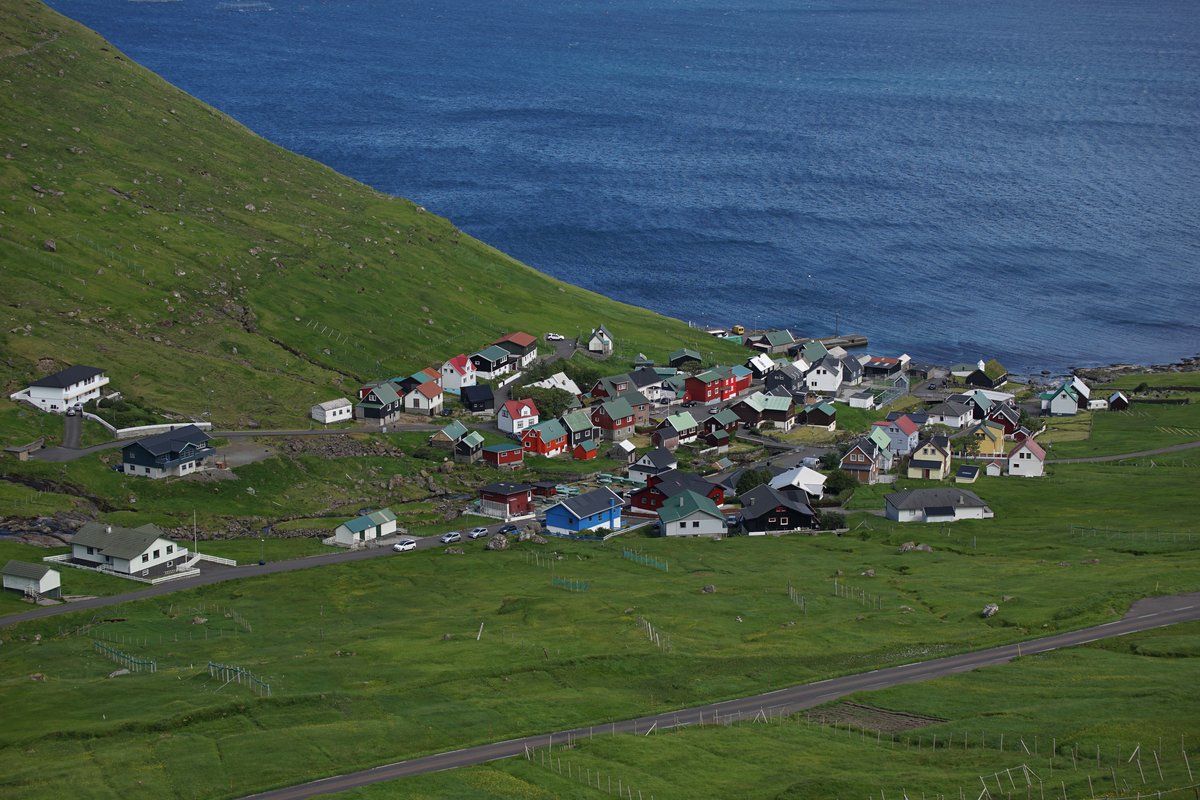 Funningur village beside a sheltered inlet with steep green mountains rising behind the houses
