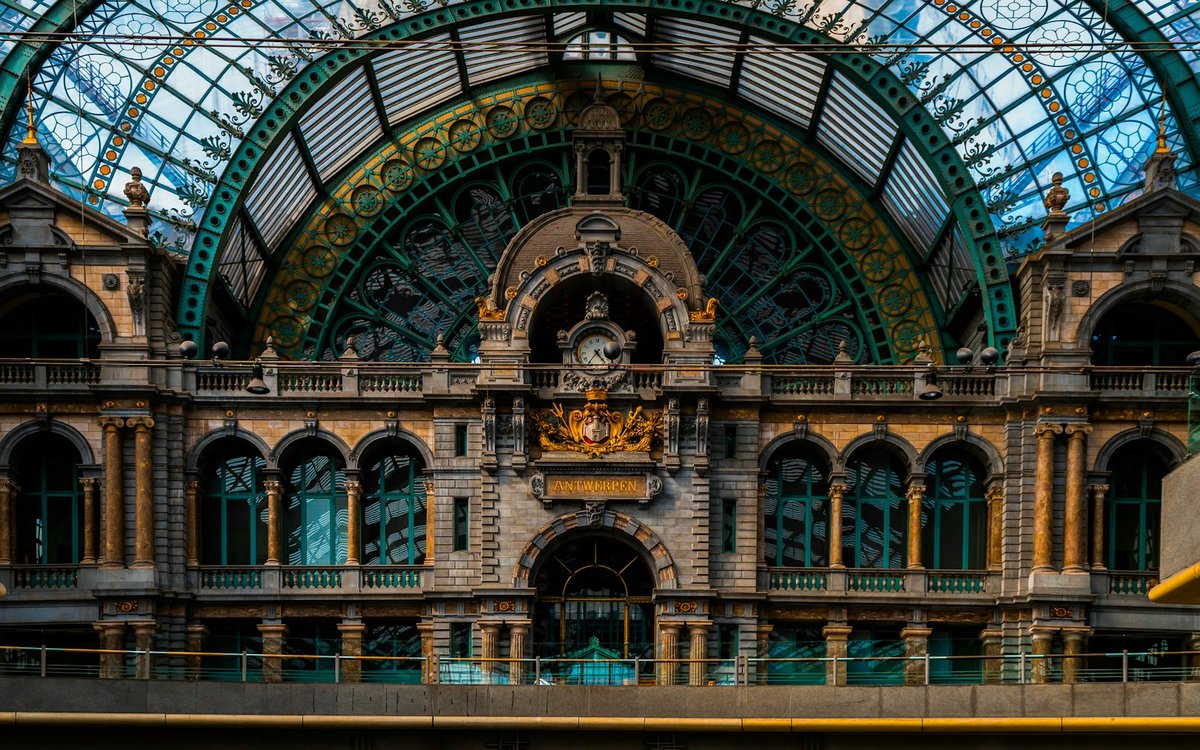 Interior of Antwerpen-Centraal station, with the clock, stone arches and glass dome