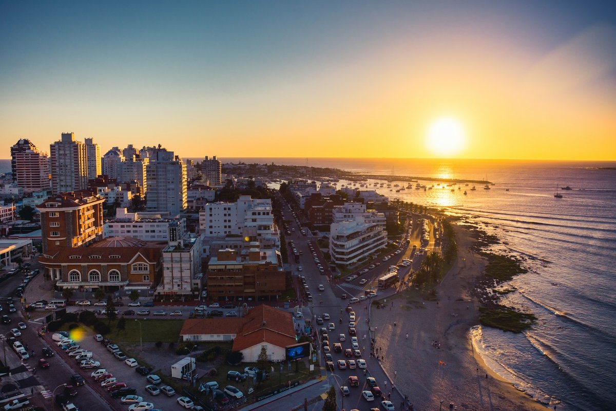 Aerial sunset over Punta del Este, with high-rise buildings, a curved beach and the Atlantic Ocean